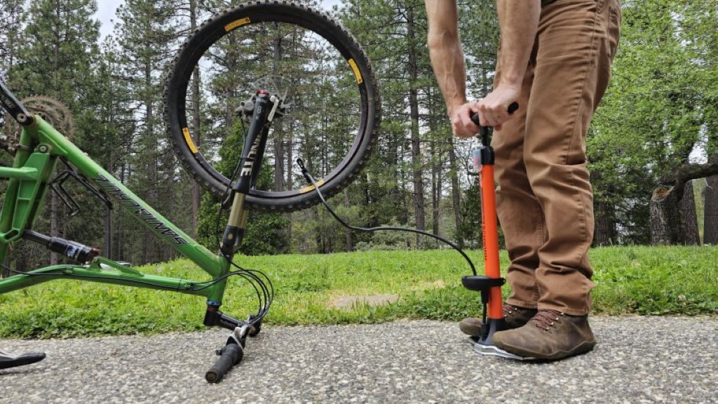 Mountain biker using an air pump to inflate tire on a trail ride