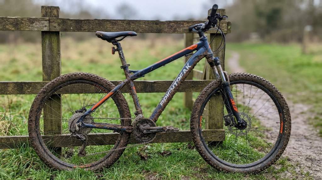 Cleaning a muddy Brightpeak 26 Inch Mountain Bike with a brush and soap