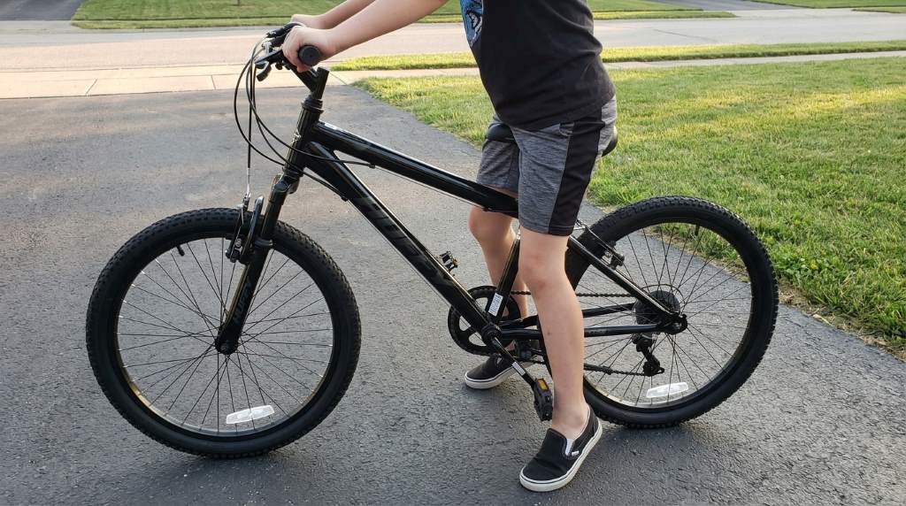 Parent measuring a child’s inseam for a Huffy Stone mountain bike